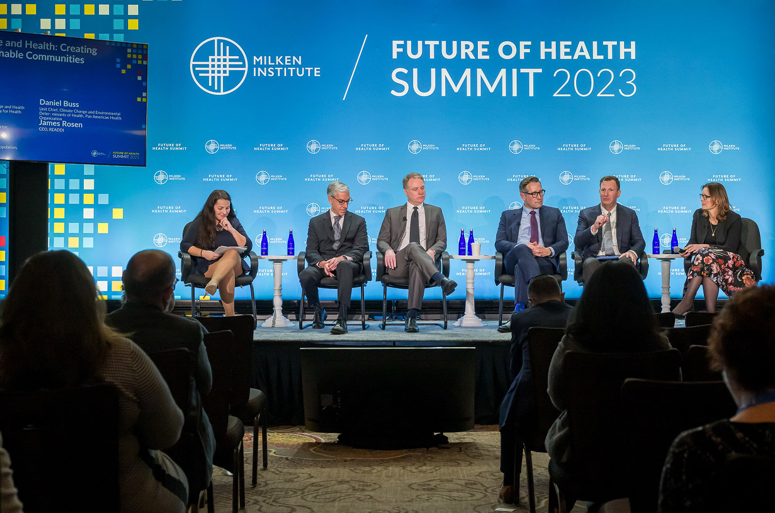 Six people sit on a stage during a panel discussion.