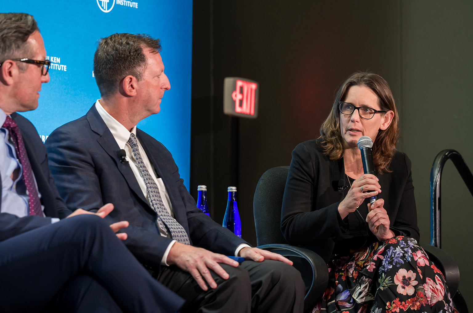 Woman holding microphone speaks on a panel.