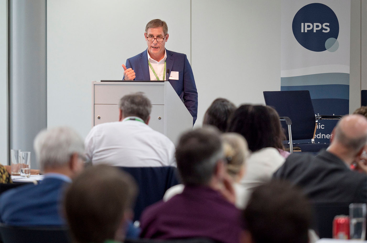 Dr. Nat Moorman behind lectern addressing a roomful of people at Therapeutics Coalition workshop in London.