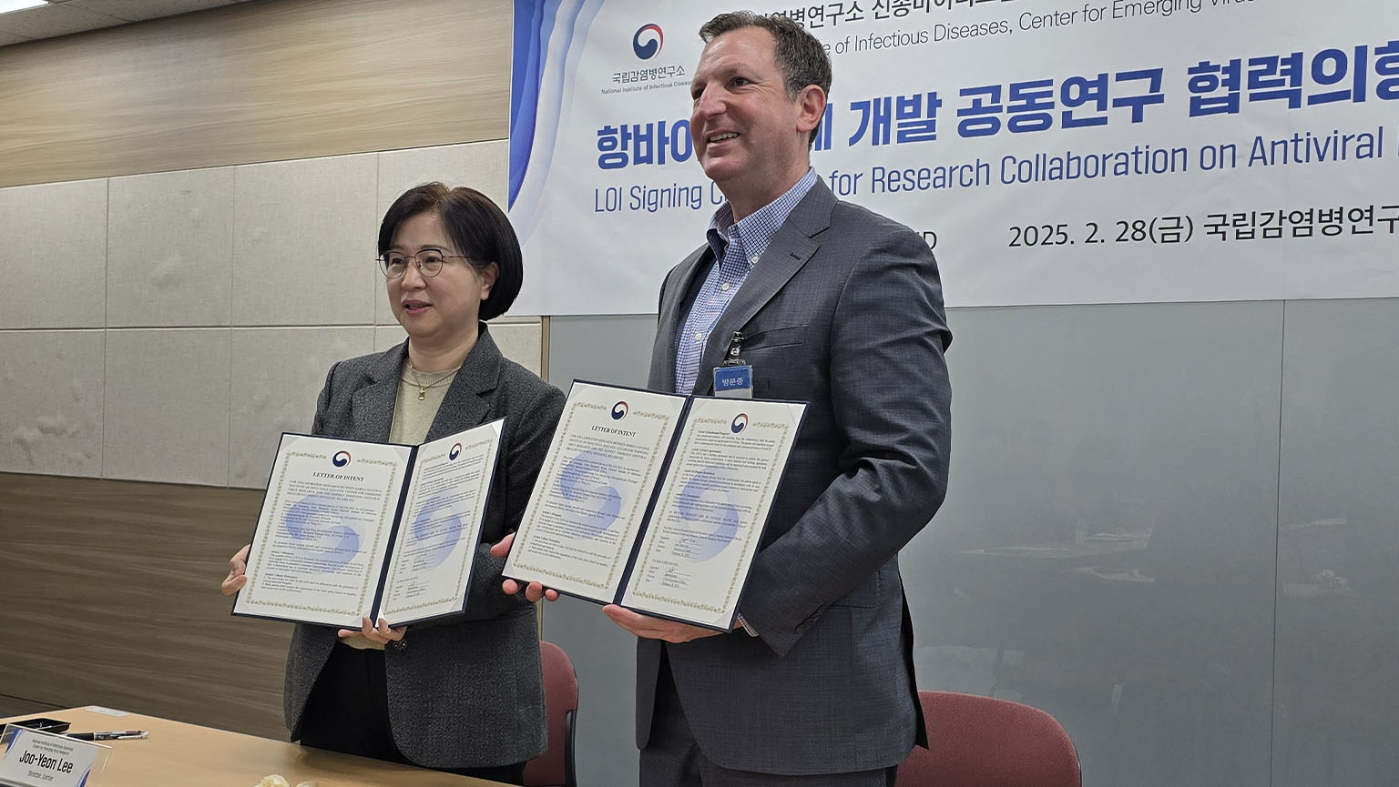 Two people posing with signed documents